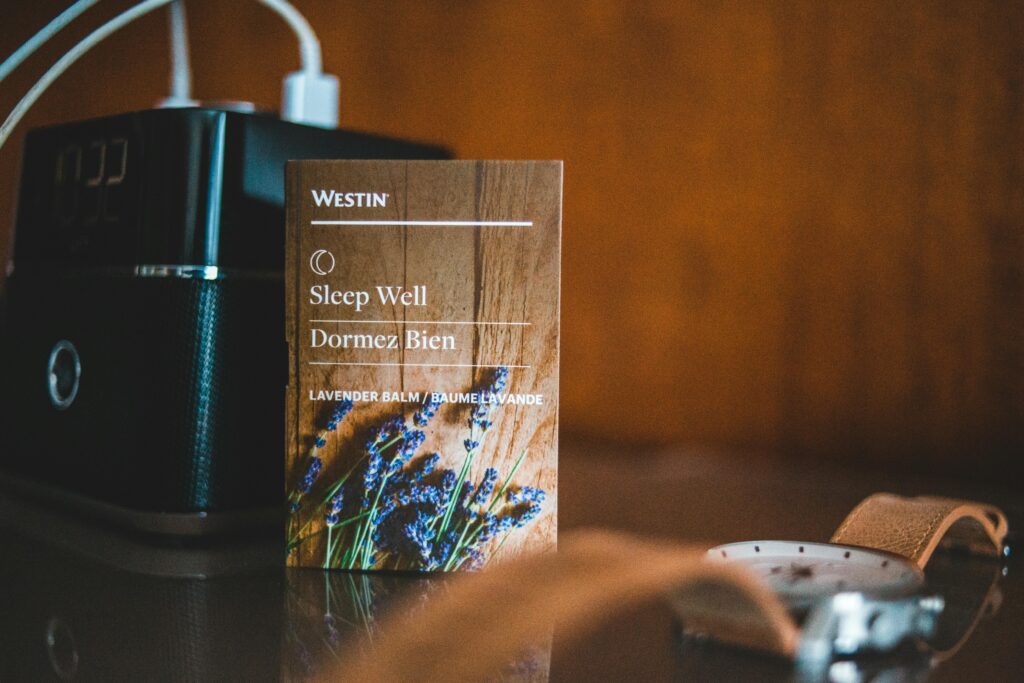 A nightstand featuring a lavender sleep aid card, a classic wristwatch, and speakers for a relaxing atmosphere.